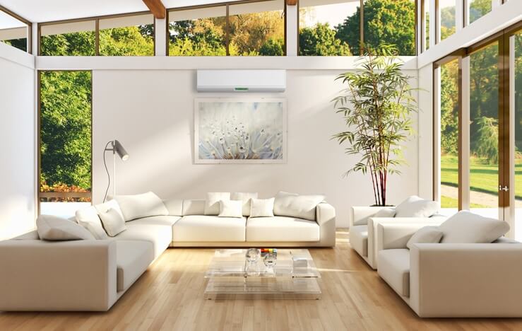 A bright living room with many windows and a ductless AC unit.