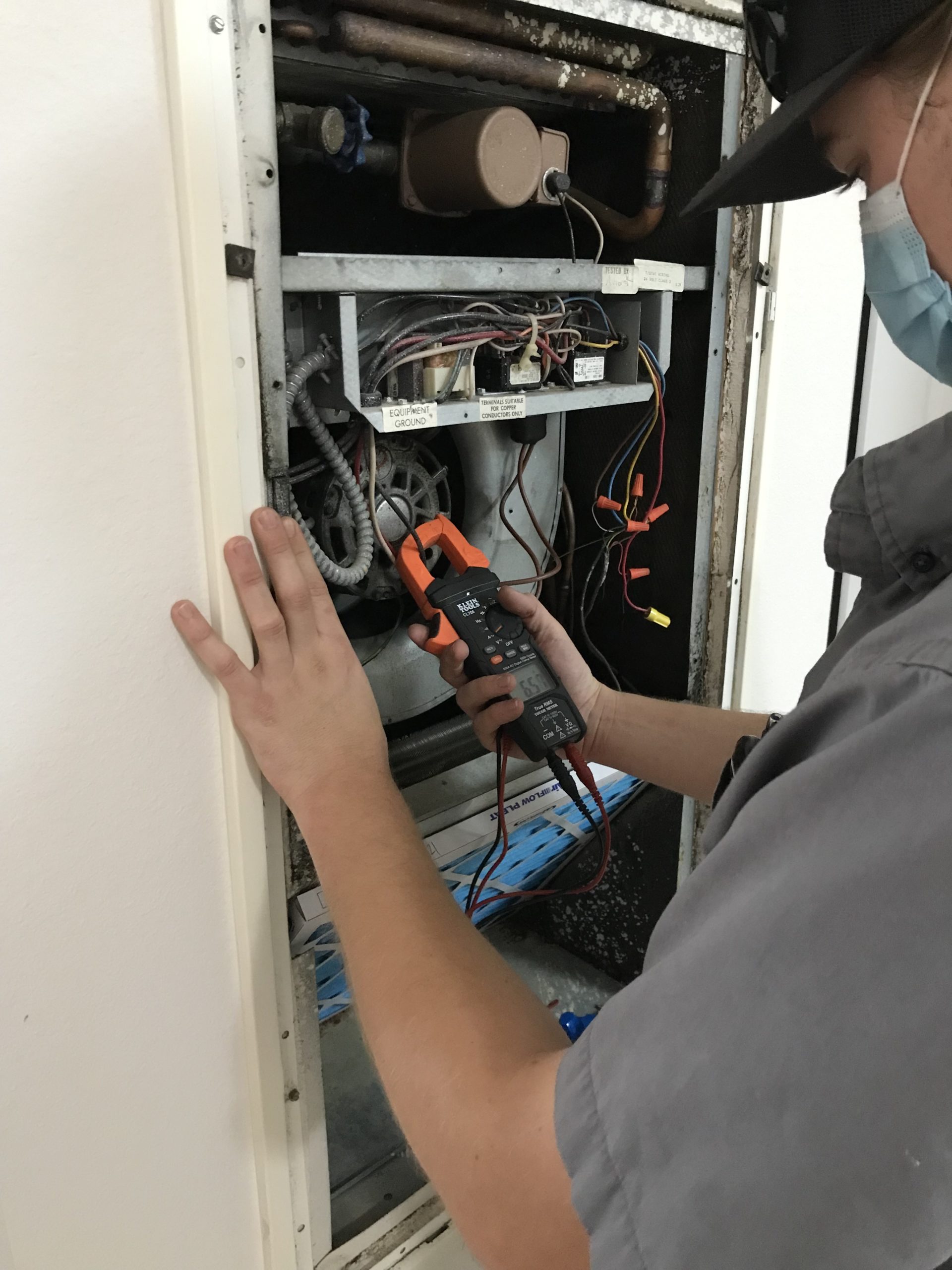 A Tradmasters HVAC technician repairs an AC unit.