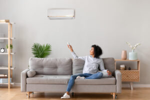 woman seated on couch using ductless heating unit