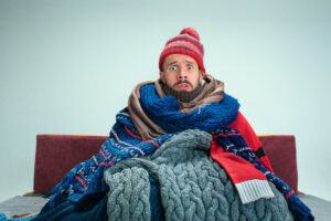 man sits bundled up on the couch