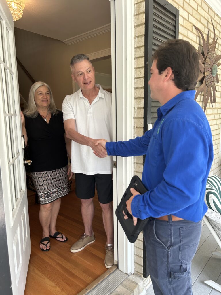 Homeowners welcoming a Trademasters Home Services technician at the front door for professional home maintenance services.