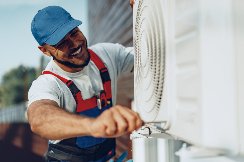 HVAC technician servicing an outdoor air conditioning unit before summer